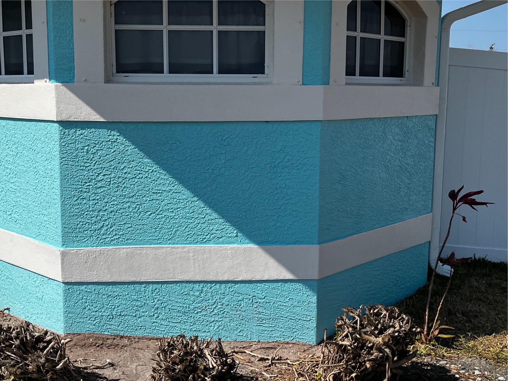 A blue and white house with a white fence in the background