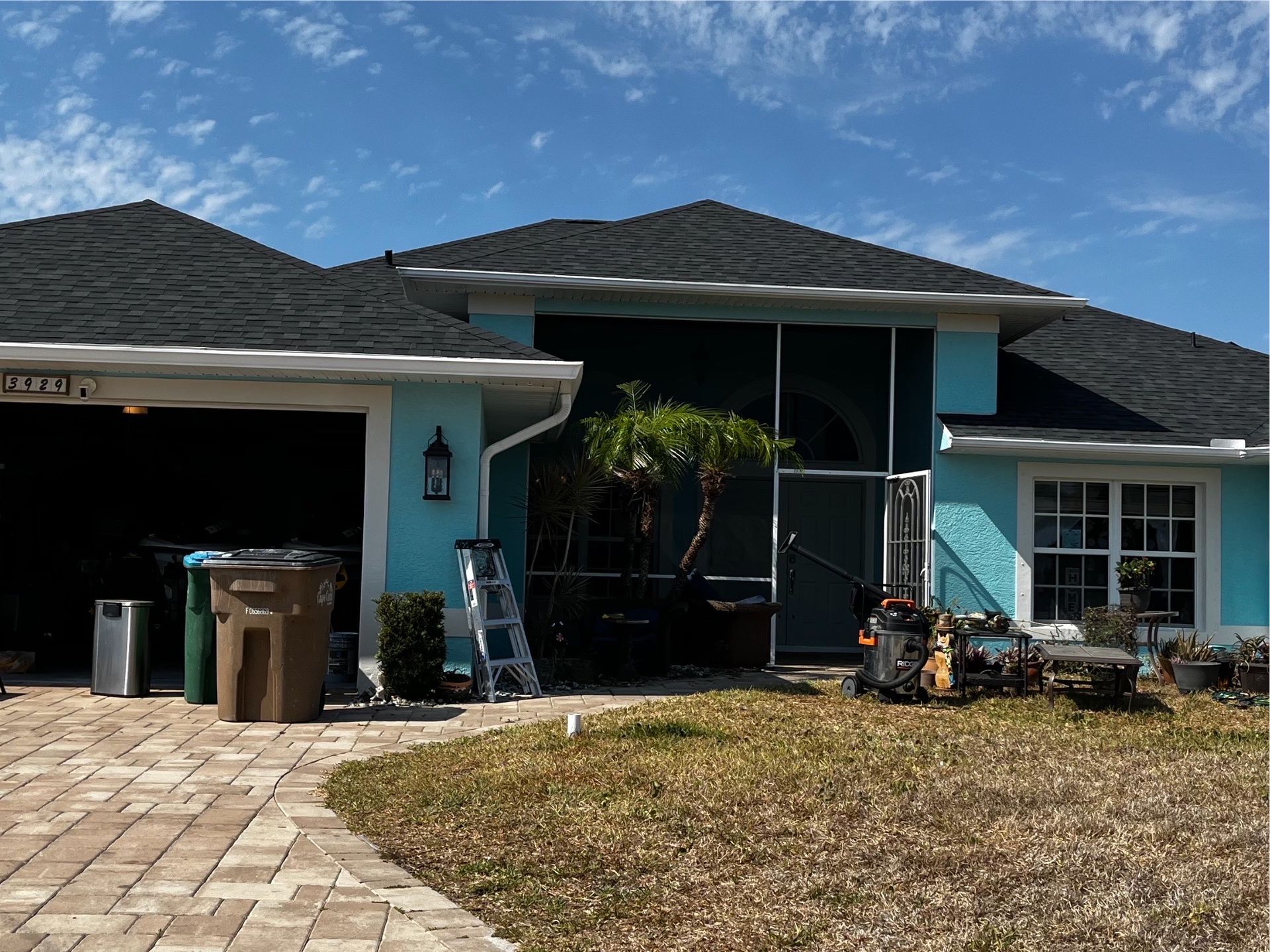 A blue house with a black roof and a screened in porch.