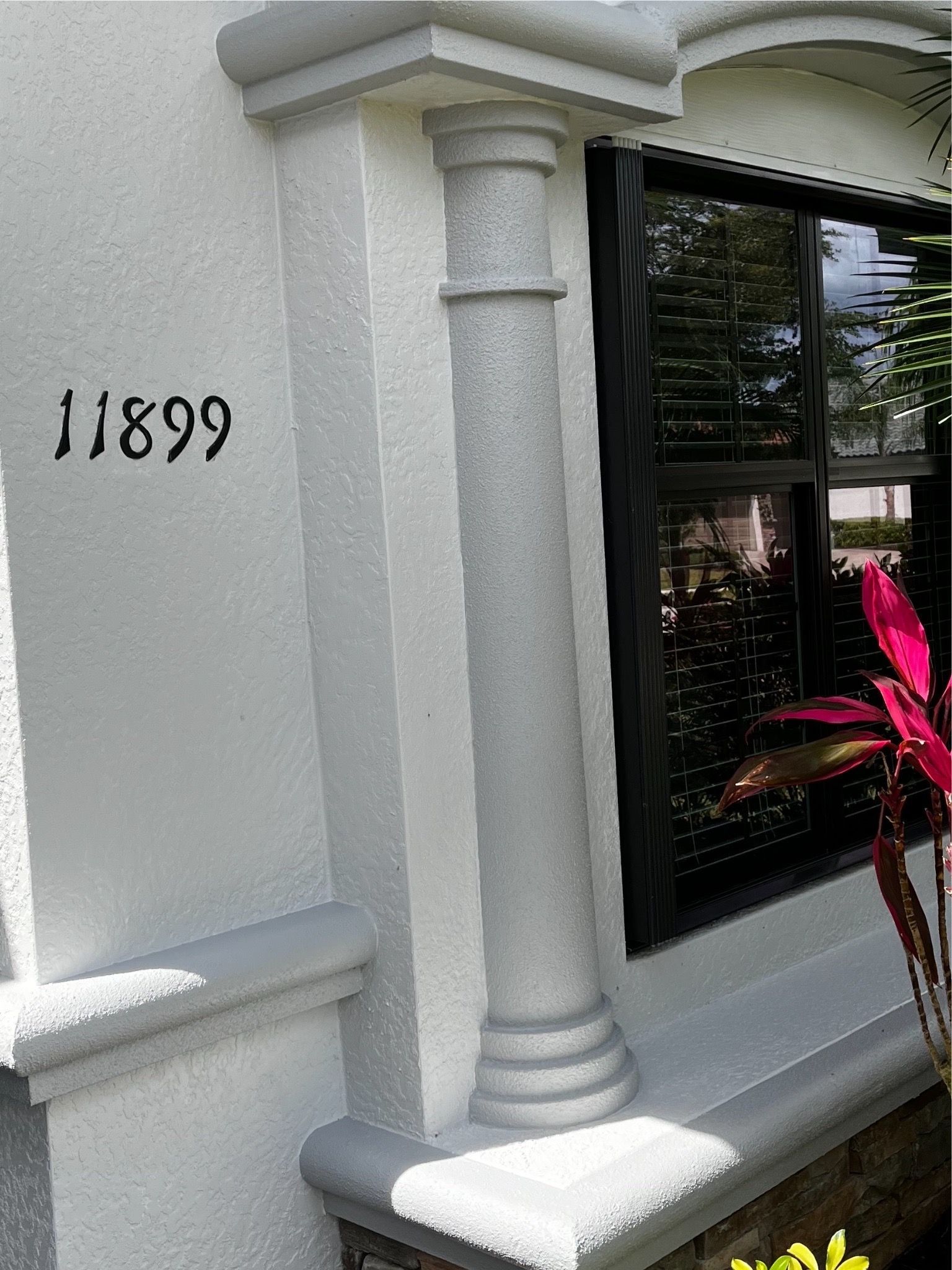 A white building with a window and a pillar with the number 11899 on it