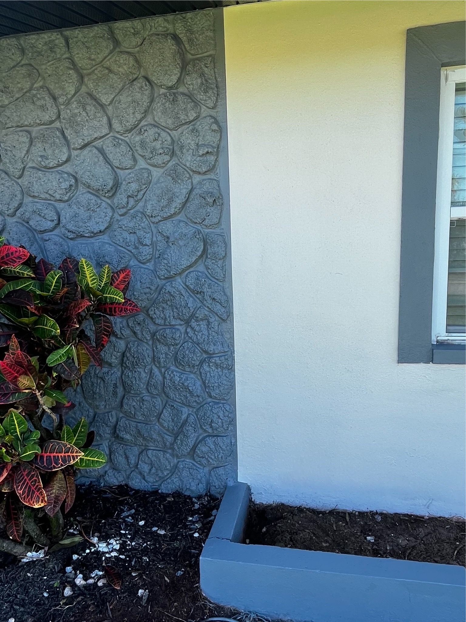 A house with a window and a potted plant in front of it