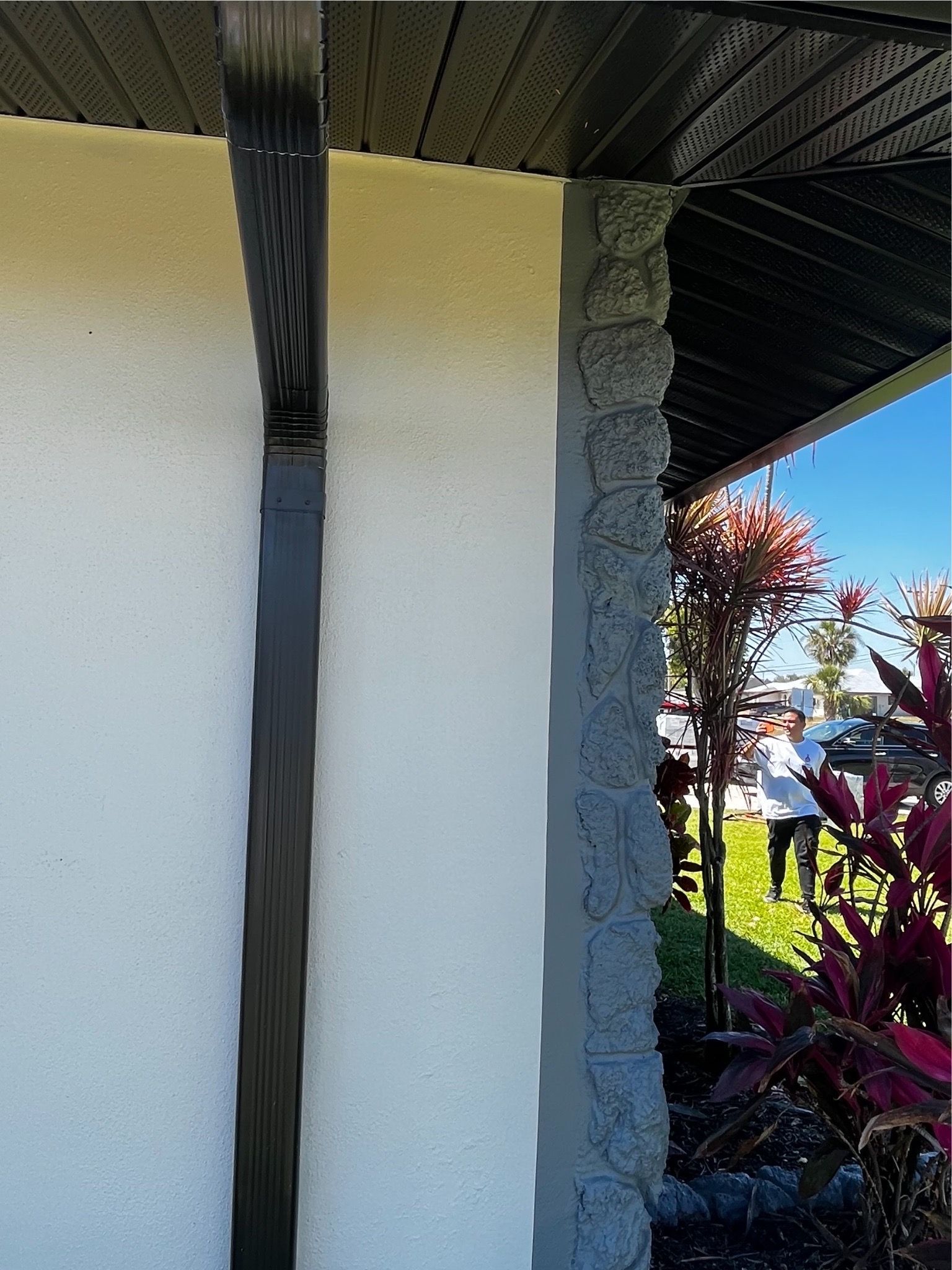 A white building with a black gutter on the side of it.