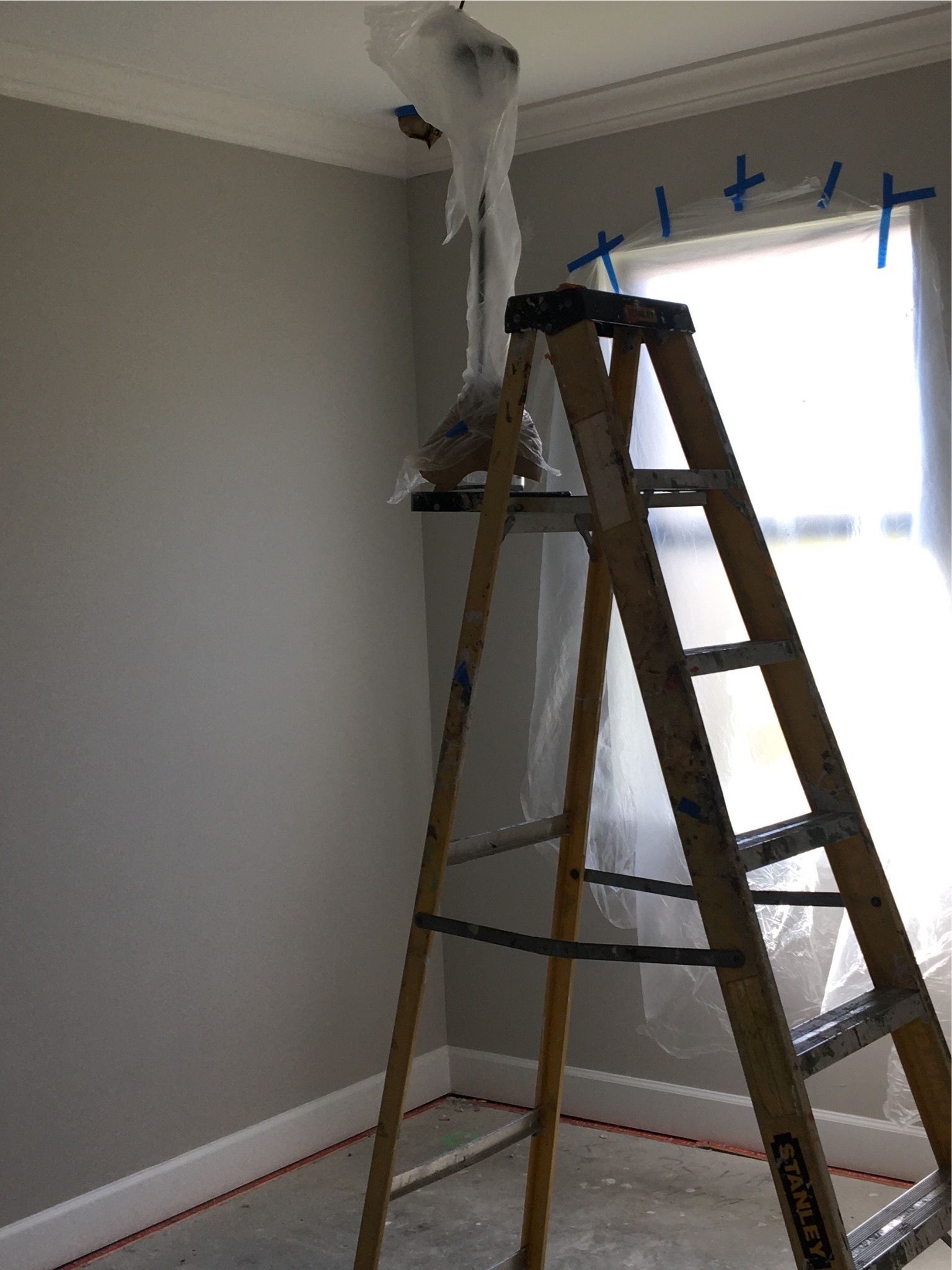 A wooden ladder is sitting in a room next to a window.