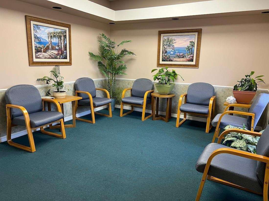 A waiting room with a lot of chairs and plants.