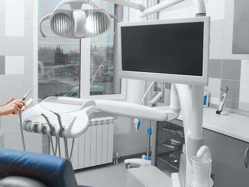 A person is sitting in a dental chair in a dental office.