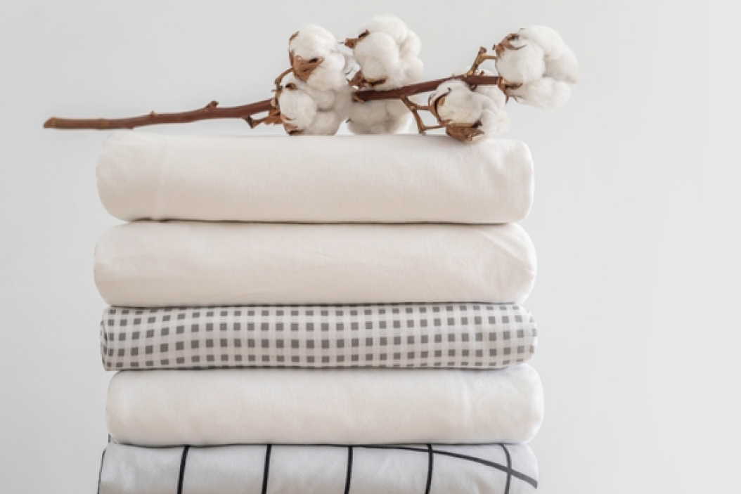 A stack of sheets with cotton flowers on top of them.