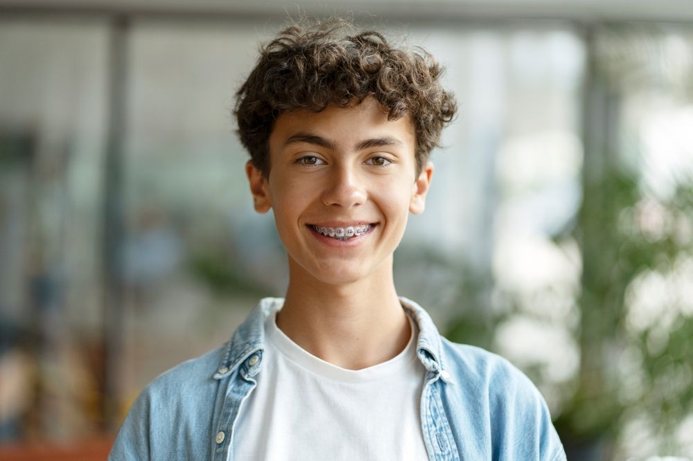 A young boy with braces on his teeth is smiling for the camera.