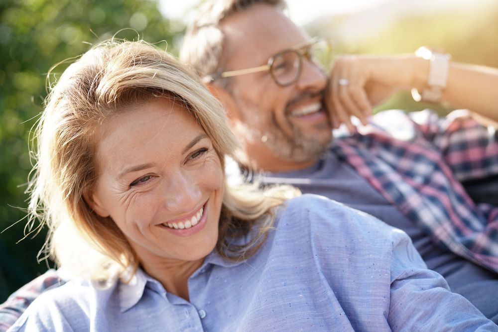 A man and a woman are sitting on a bench and smiling.