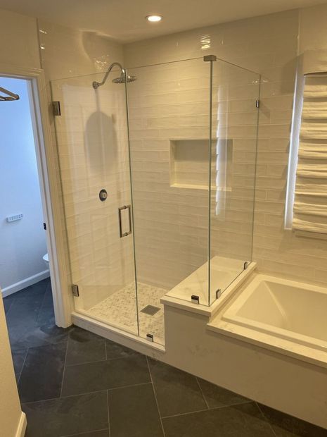 Modern bathroom with glass shower, white tile, and built-in tub.
