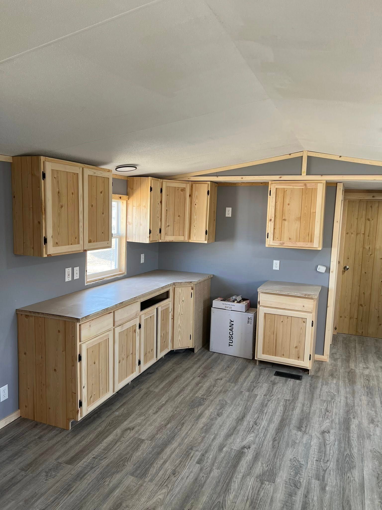 Kitchen with wood cabinets, gray walls and flooring.