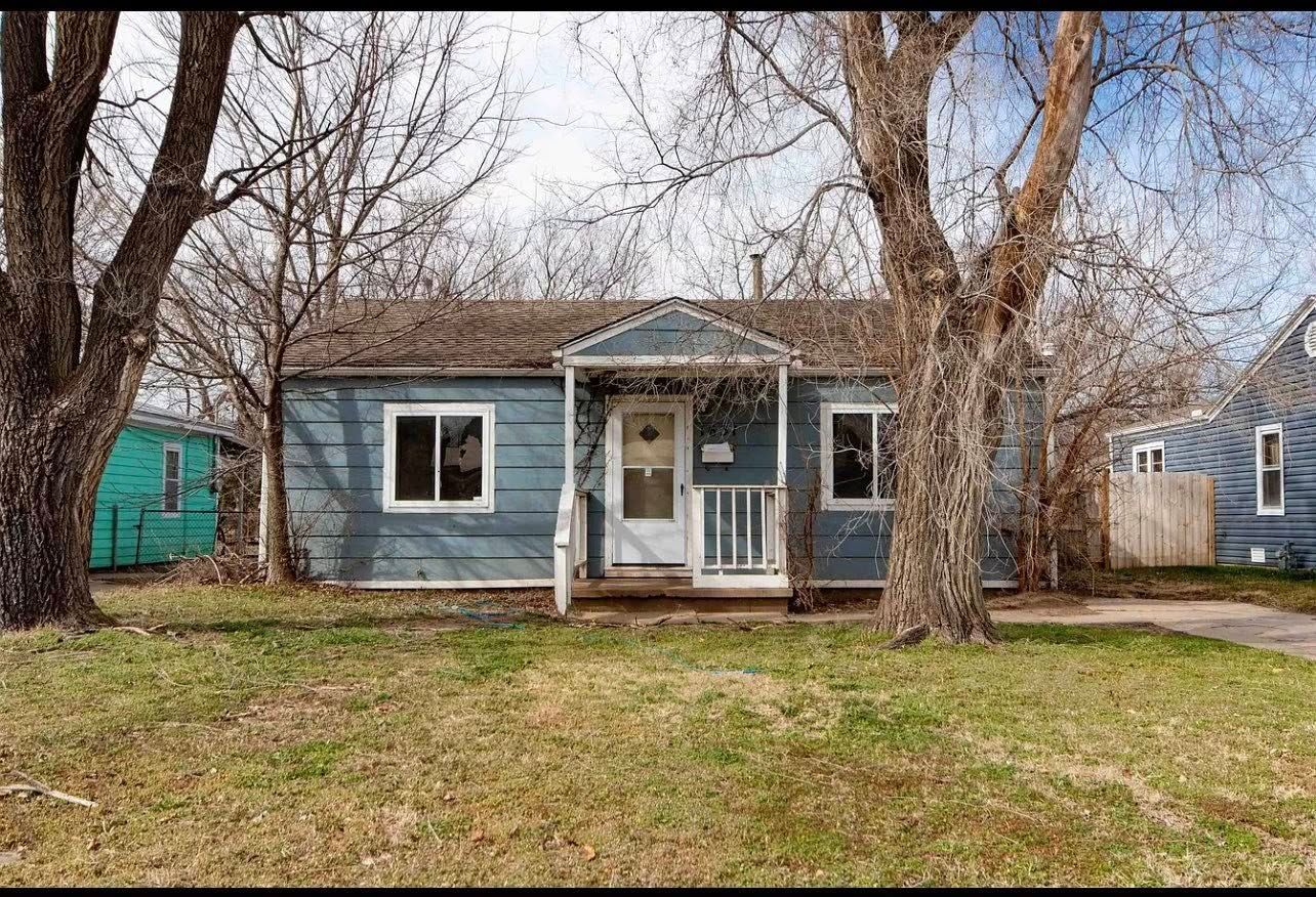 Blue house with white trim, bare trees in front, small porch.