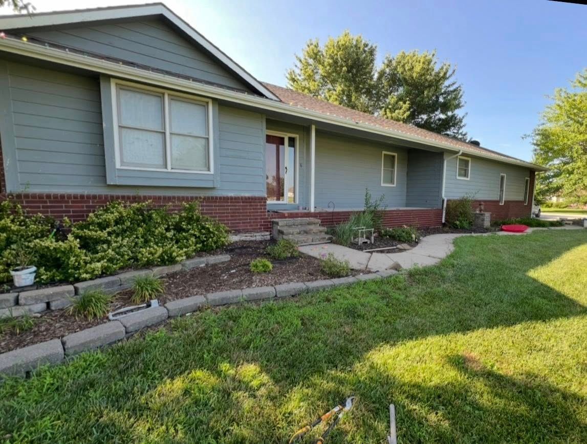 Blue house with brick, landscaping, and a walkway.