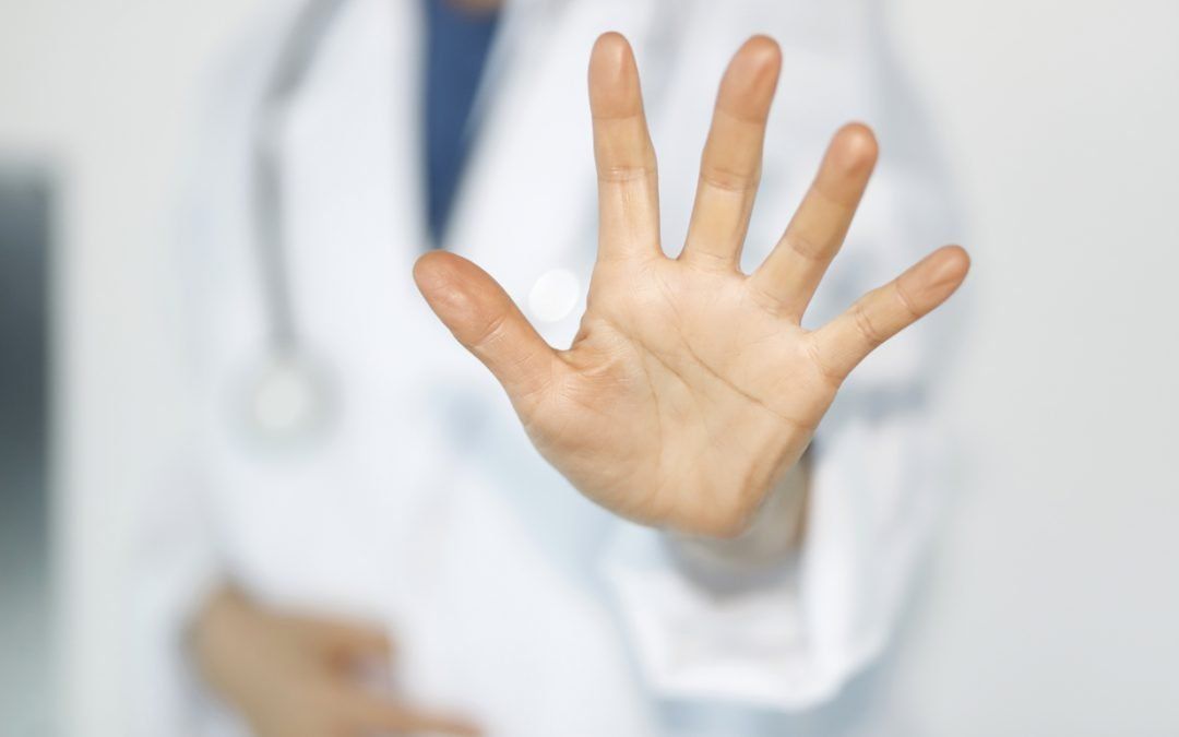 Een dokter maakt met zijn hand een stopteken.