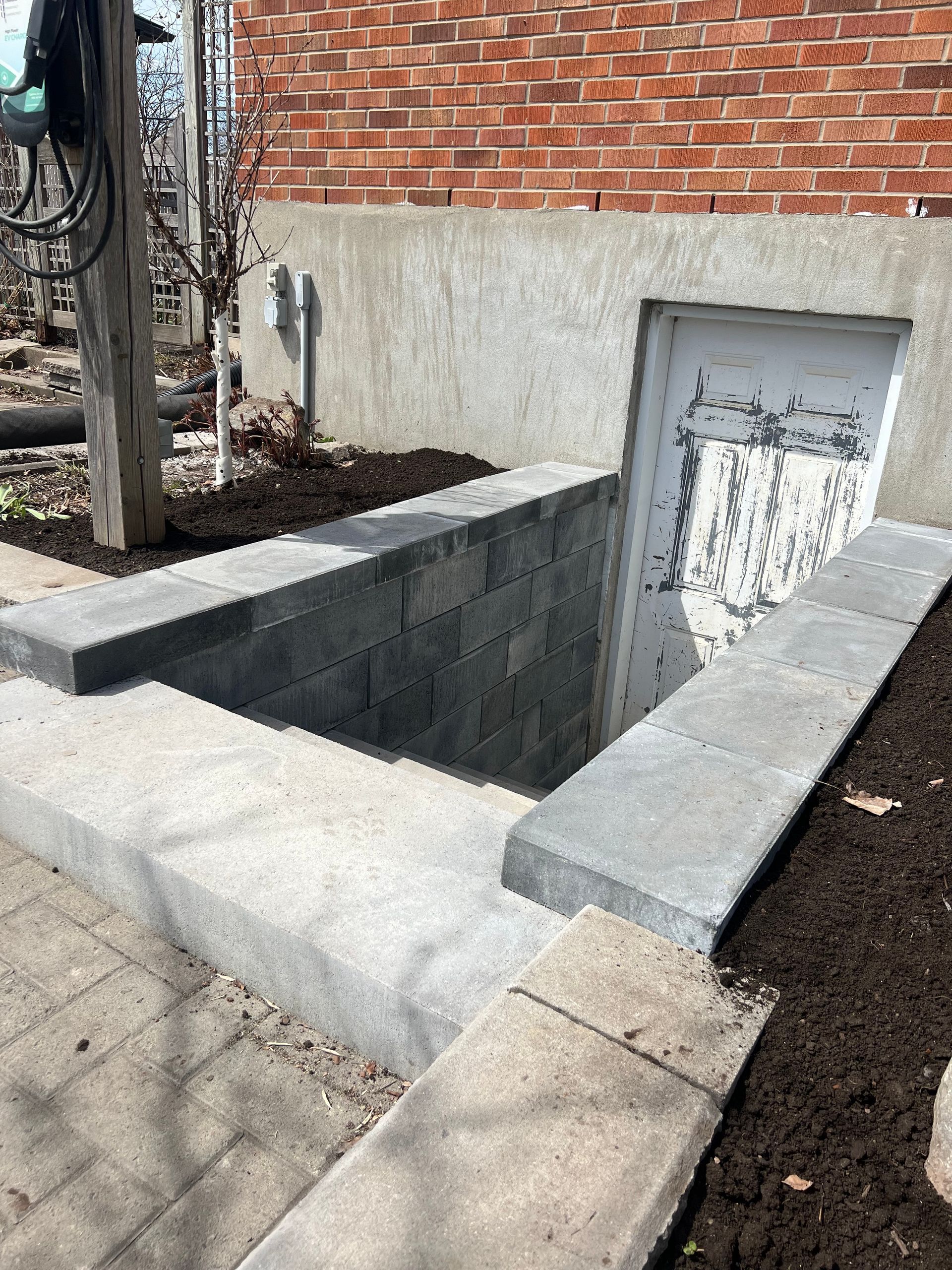 Un mur de briques avec un escalier menant à une porte de sous-sol.