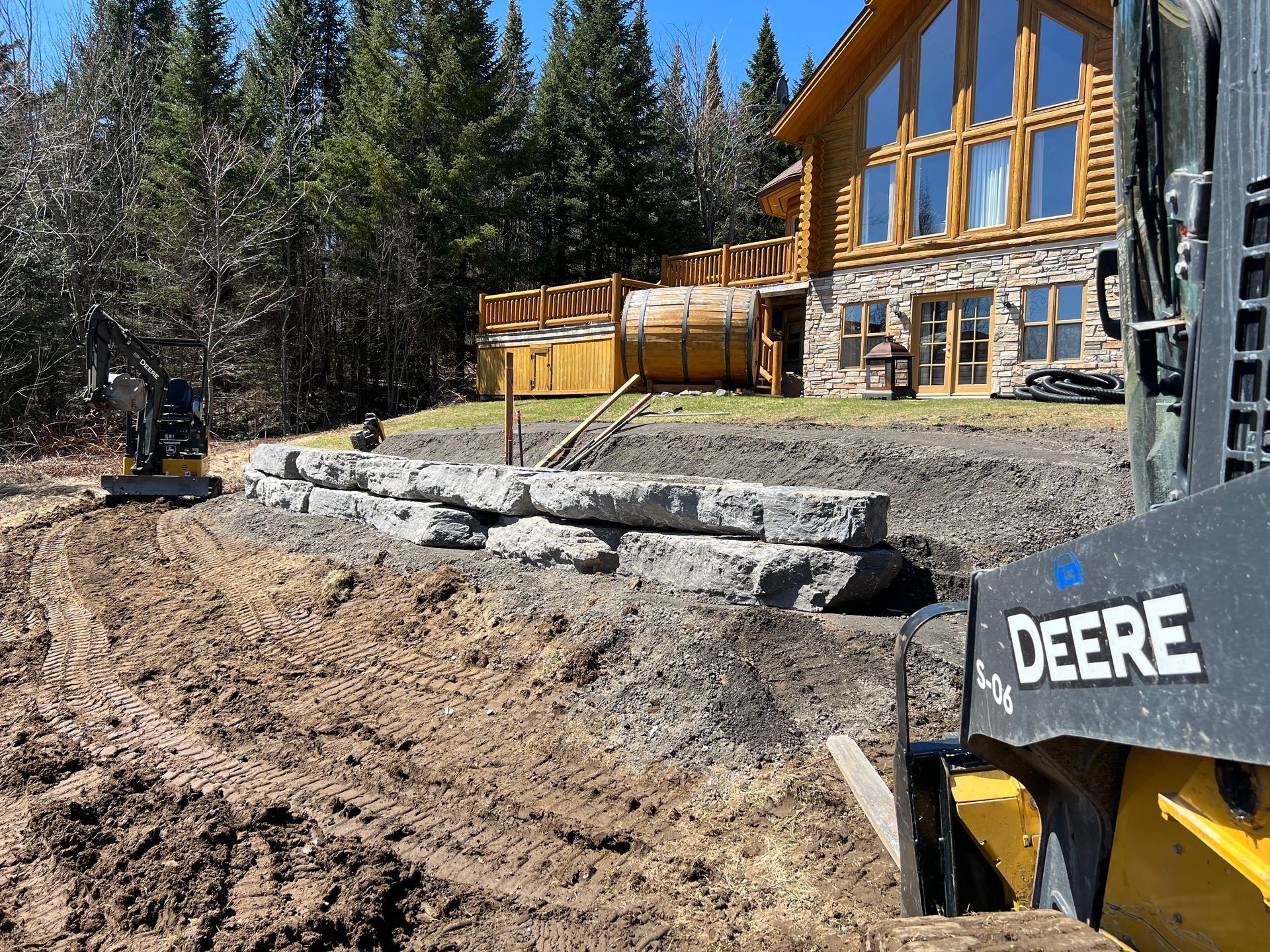 Un bulldozer Deere déplace de la terre devant une grande maison.