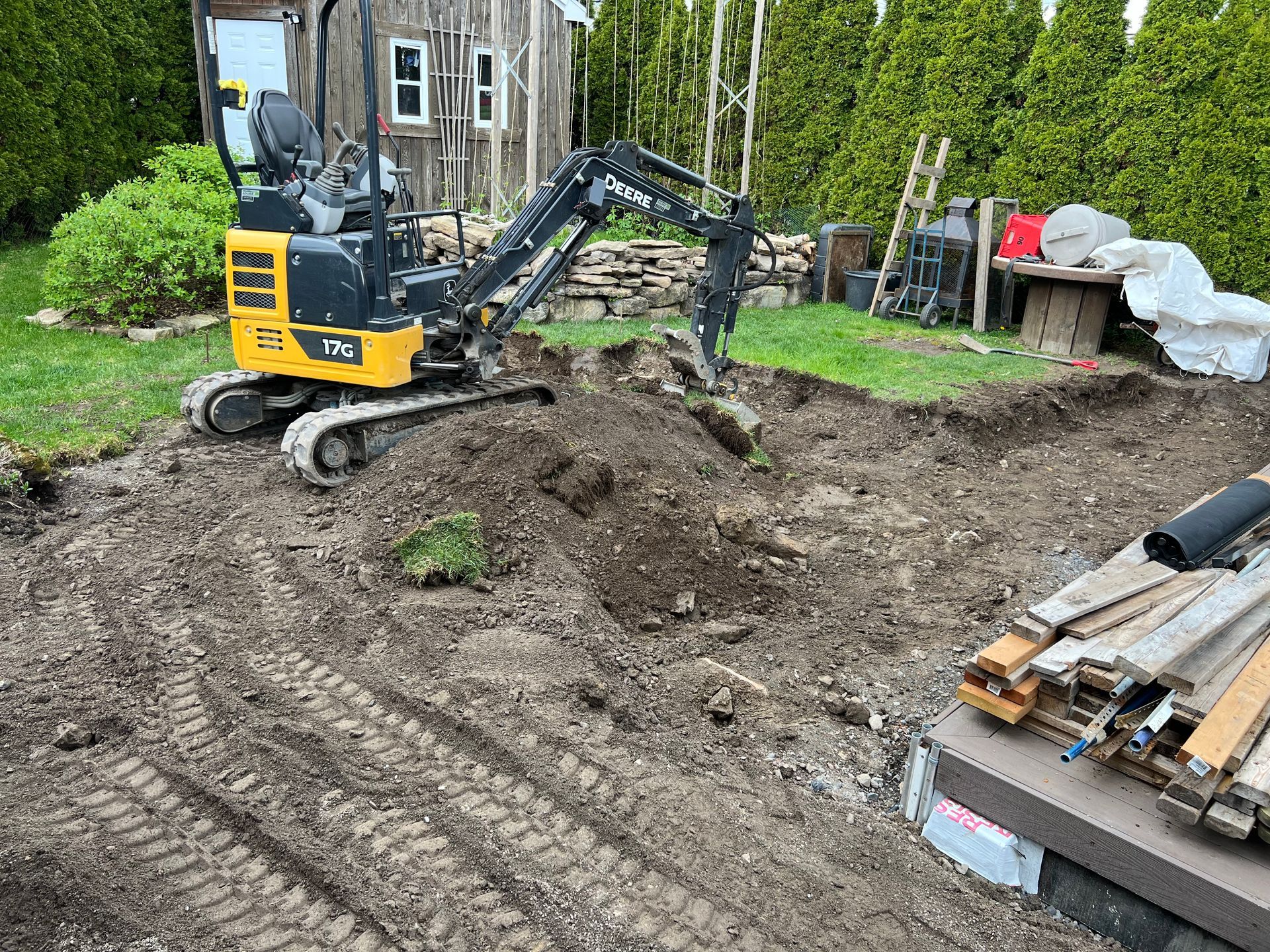 Une petite excavatrice creuse un trou dans la terre dans une cour arrière.