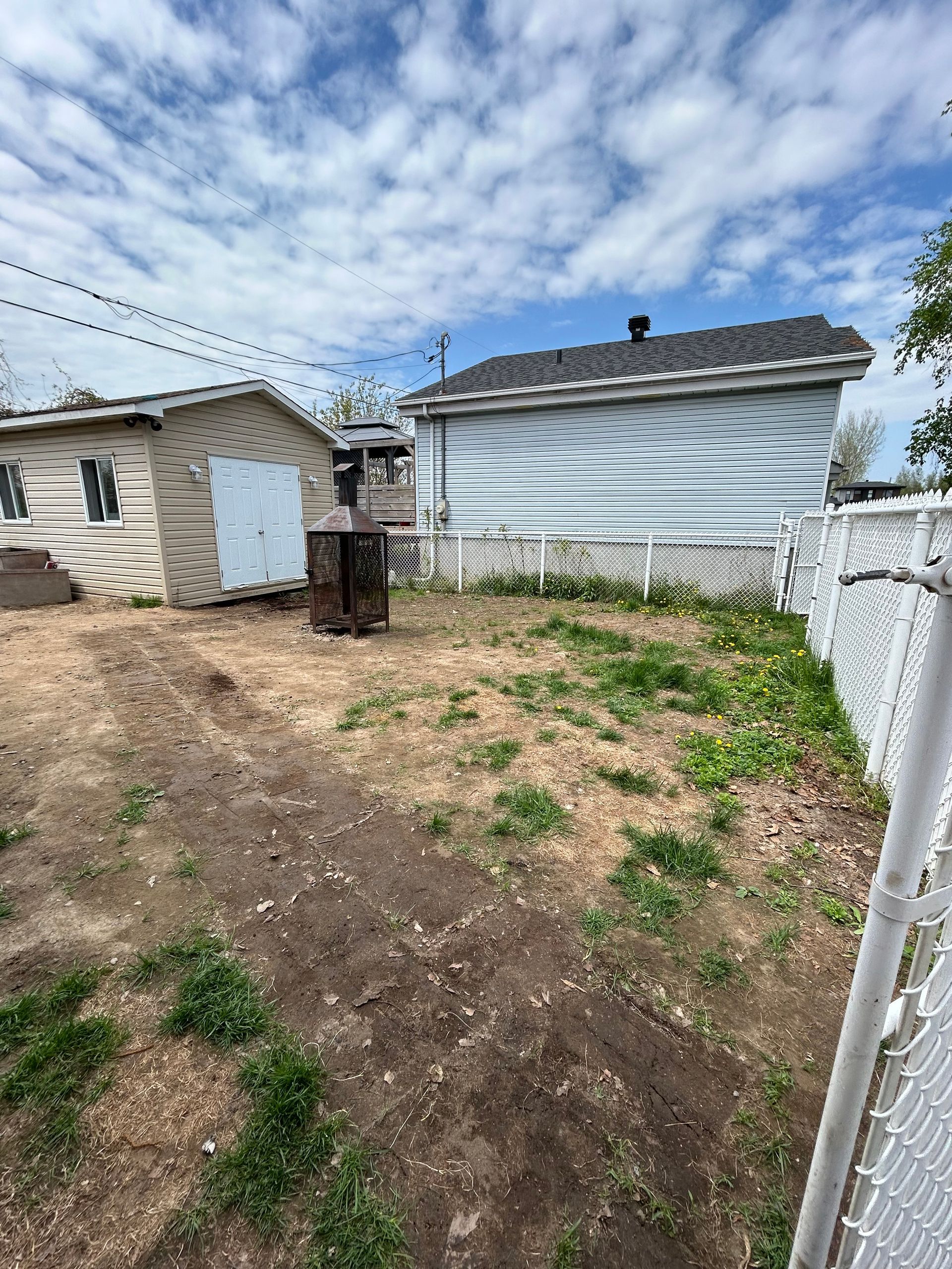 Une cour arrière avec une clôture et une maison en arrière-plan.