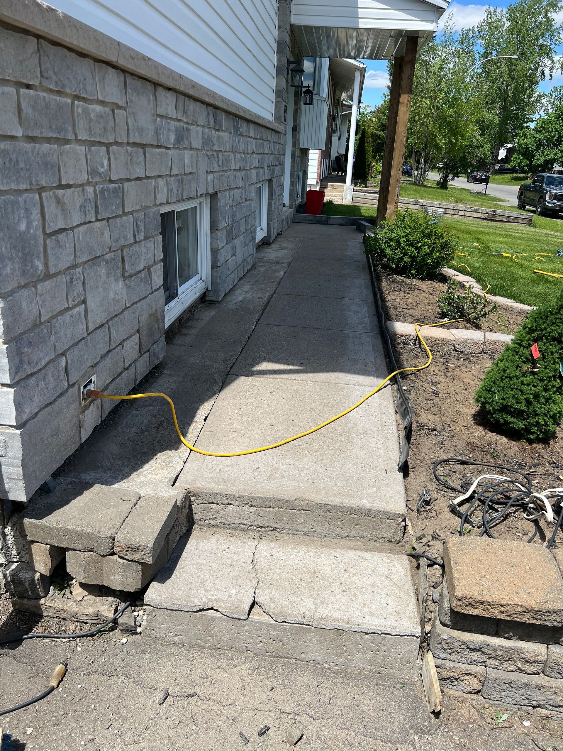 Un trottoir est en cours de construction devant une maison en briques.