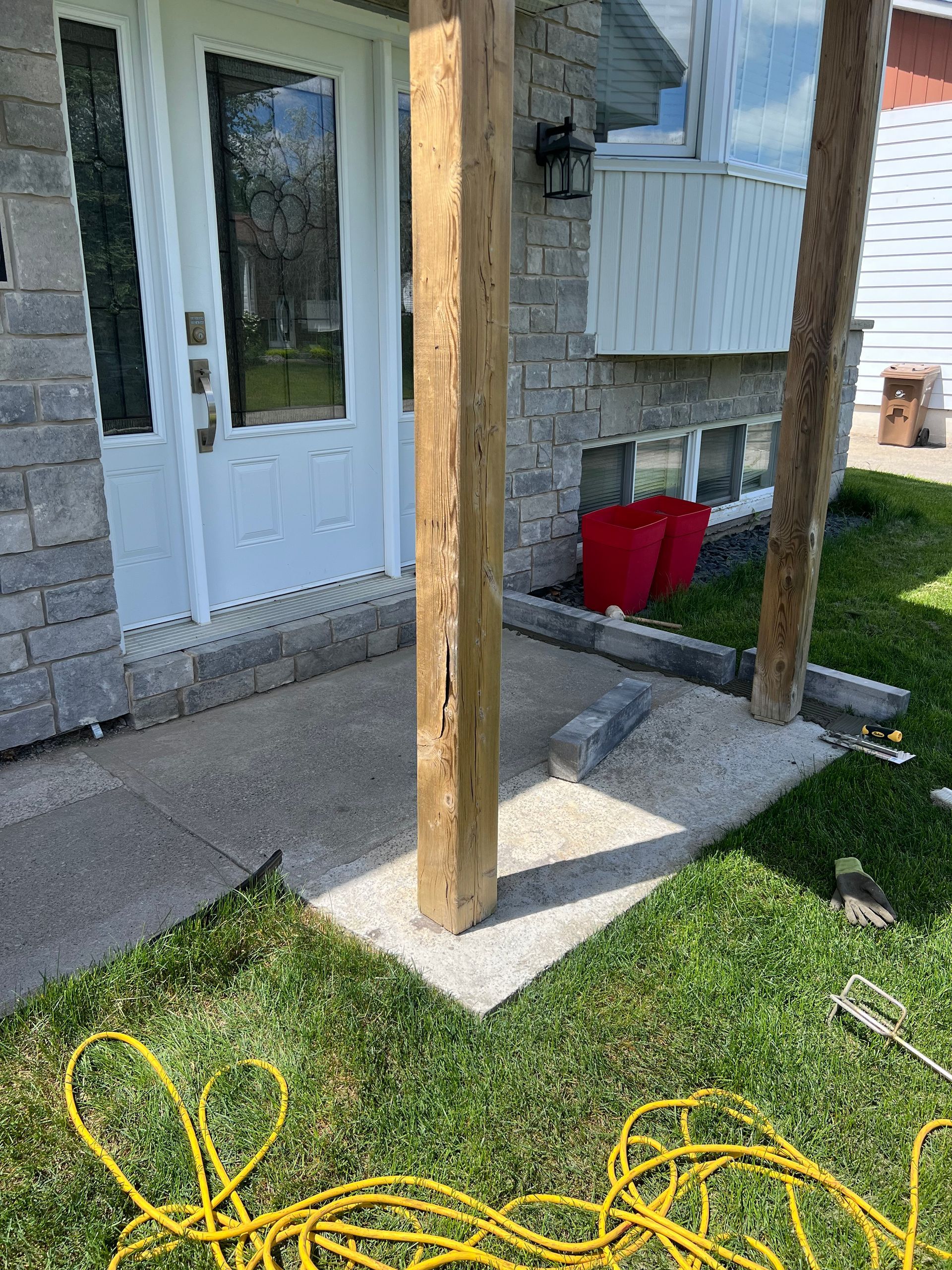 Un poteau en bois est posé dans l'herbe devant une maison.