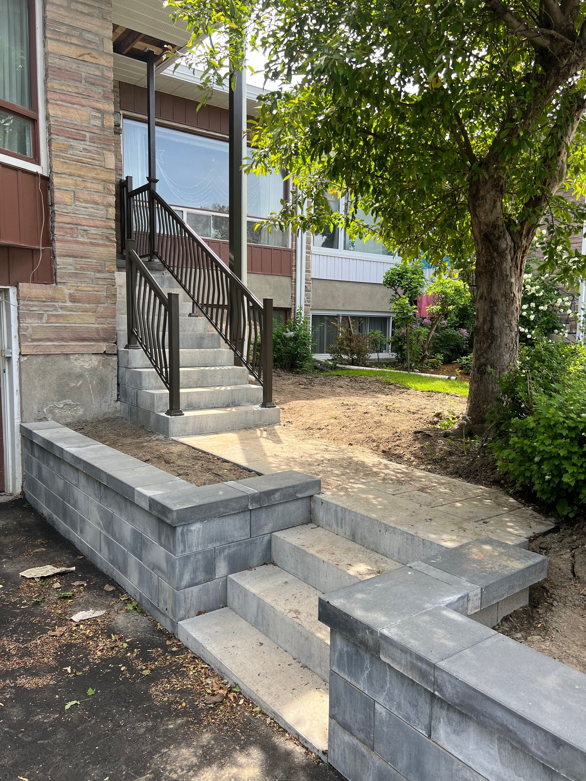 Une maison avec des escaliers et un arbre devant.