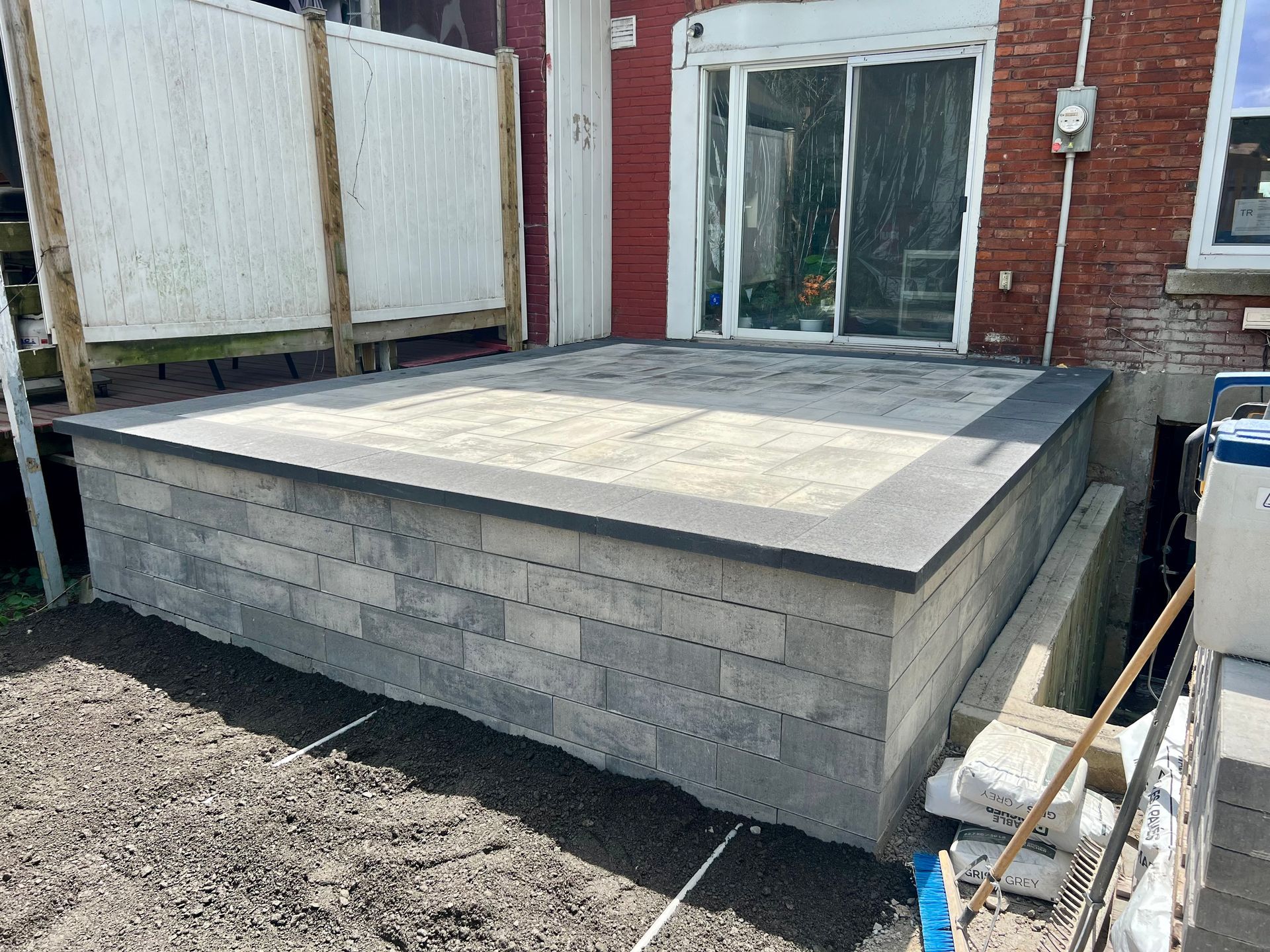 Un patio est en cours de construction dans l'arrière-cour d'une maison.