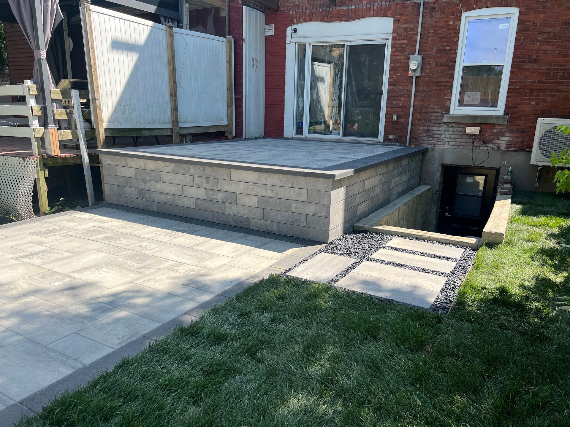 Un patio avec un mur de briques et une porte coulissante en verre dans l'arrière-cour d'une maison.