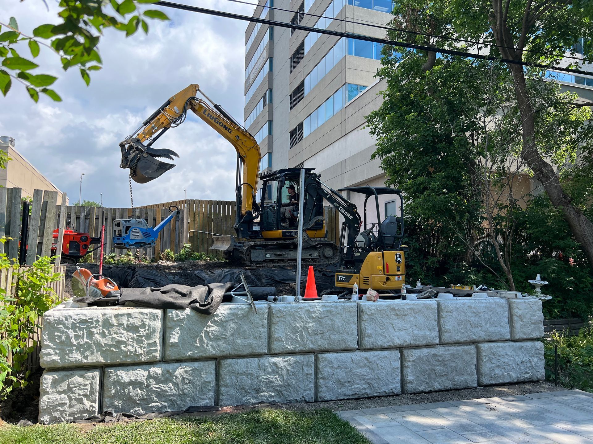 Une grande excavatrice jaune travaille sur un mur en béton.