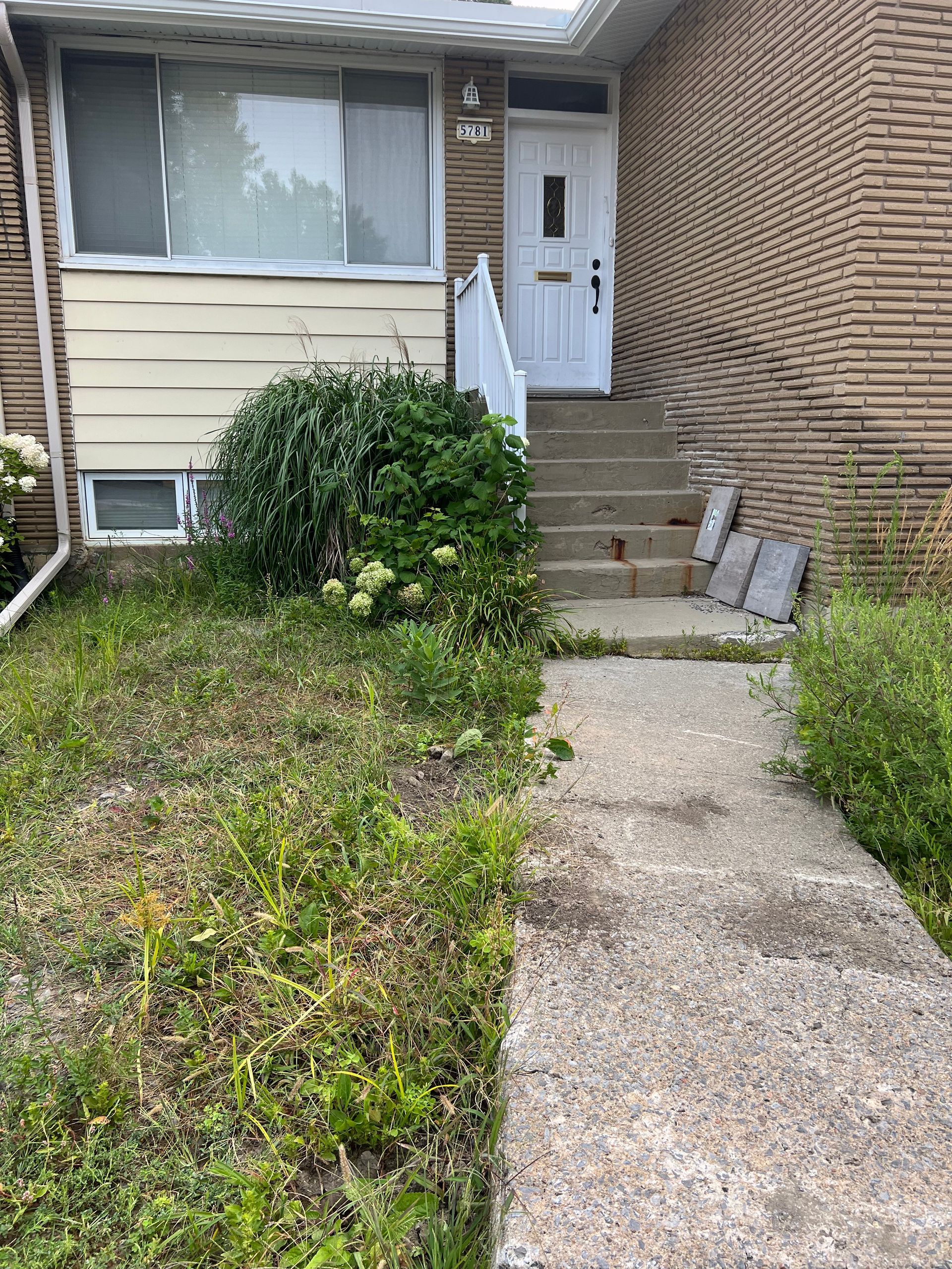 Une maison en brique avec une allée en béton menant à la porte d'entrée.
