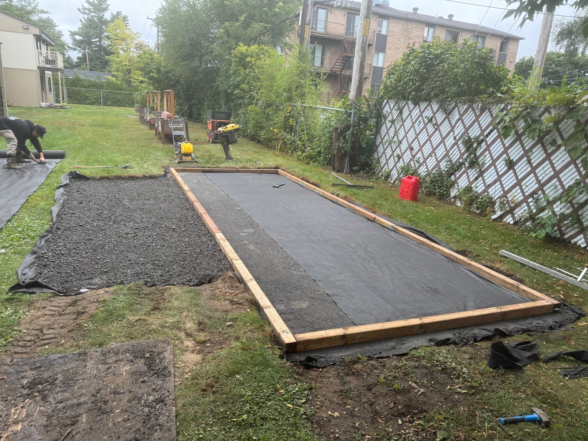Un homme travaille sur une allée en béton dans une cour arrière.