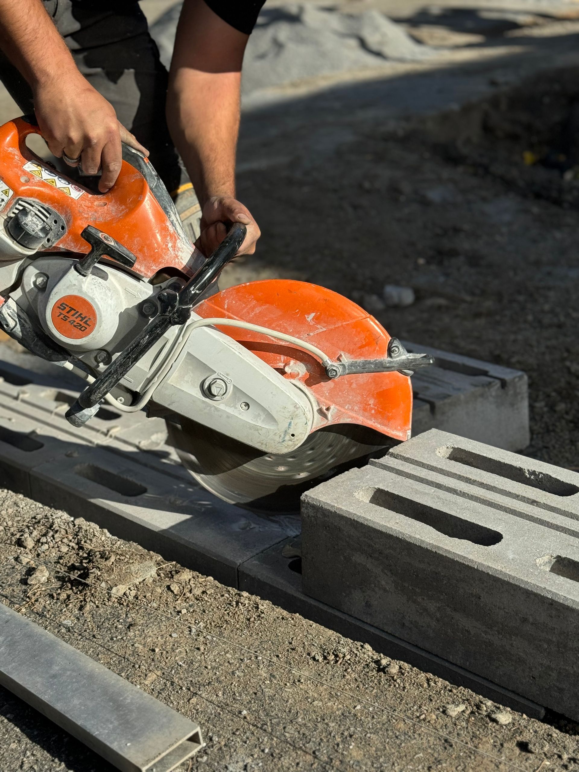 Un homme utilise une scie circulaire pour couper des blocs de béton.