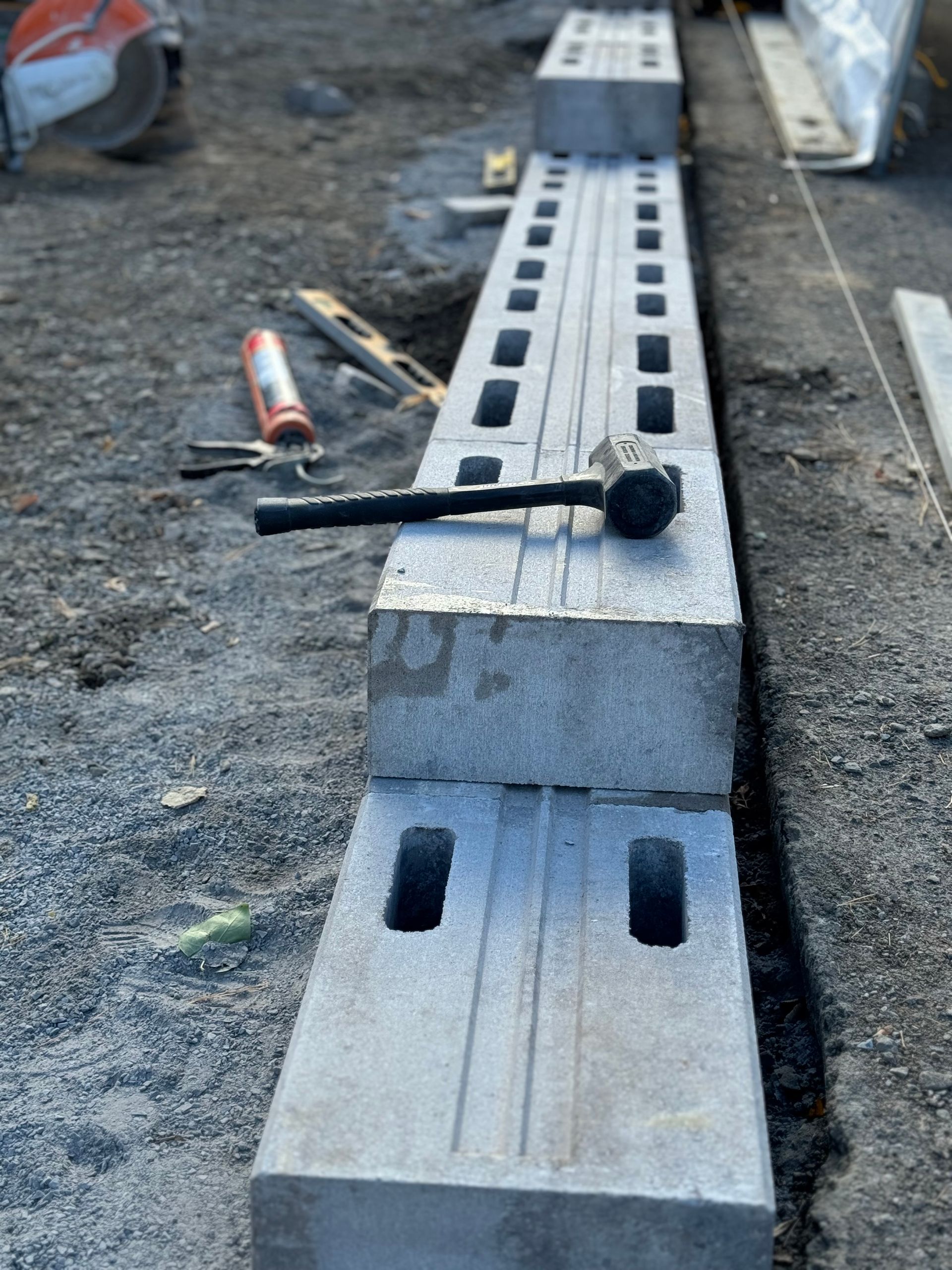 Un marteau est posé sur une rangée de blocs de béton