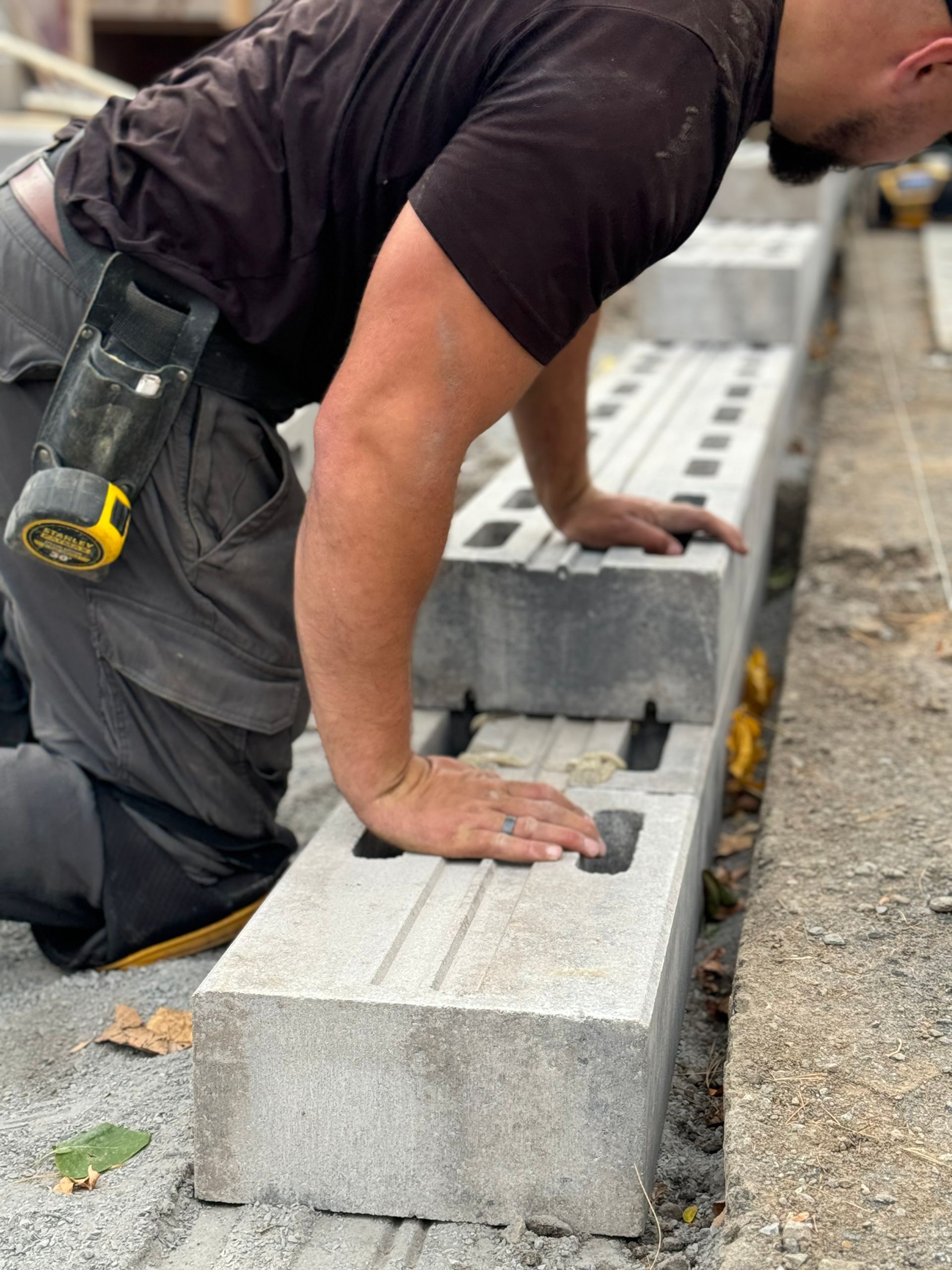 Un homme est à genoux et travaille sur un bloc de béton.