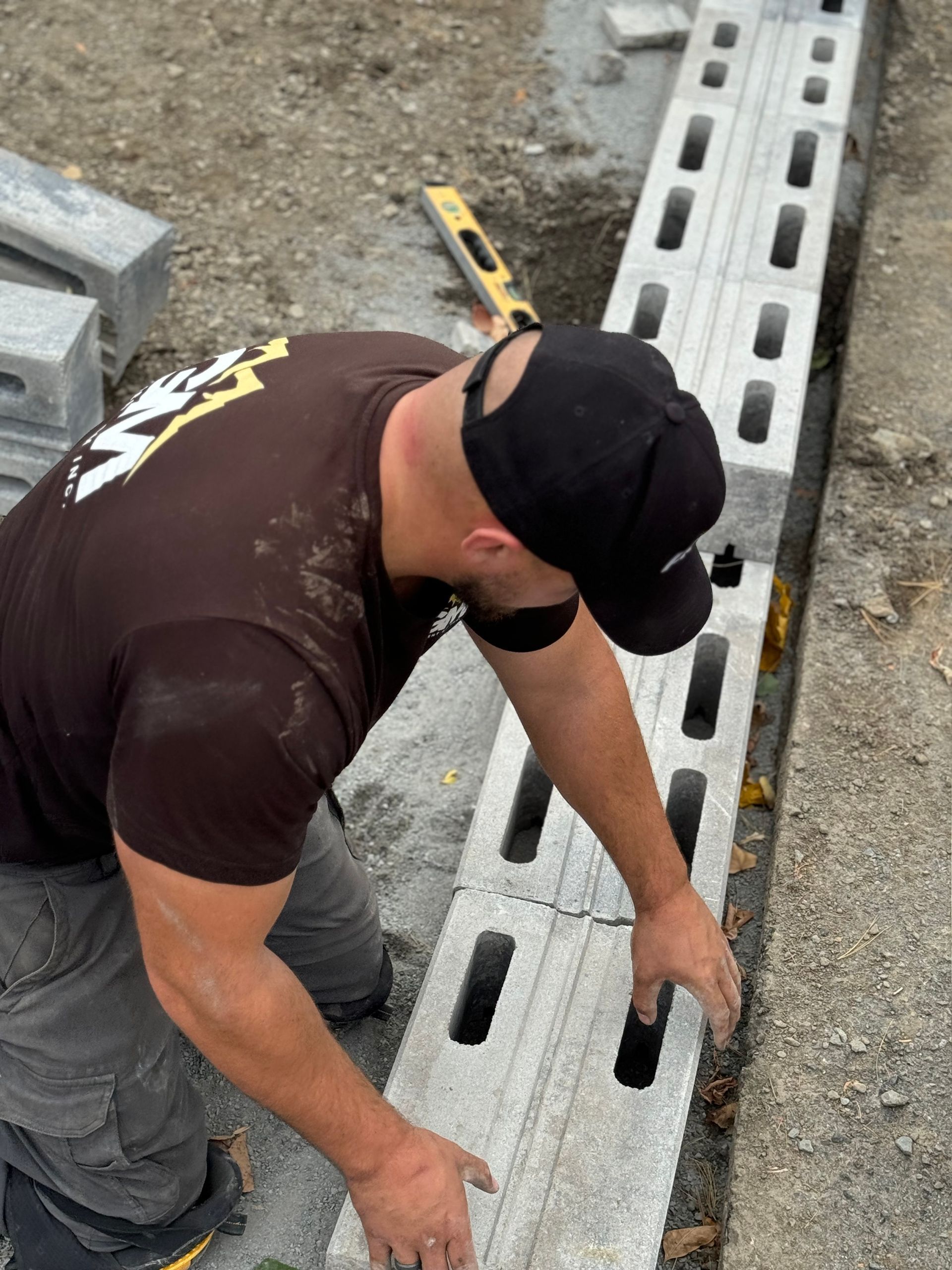 Un homme portant un chapeau noir travaille sur un mur en béton
