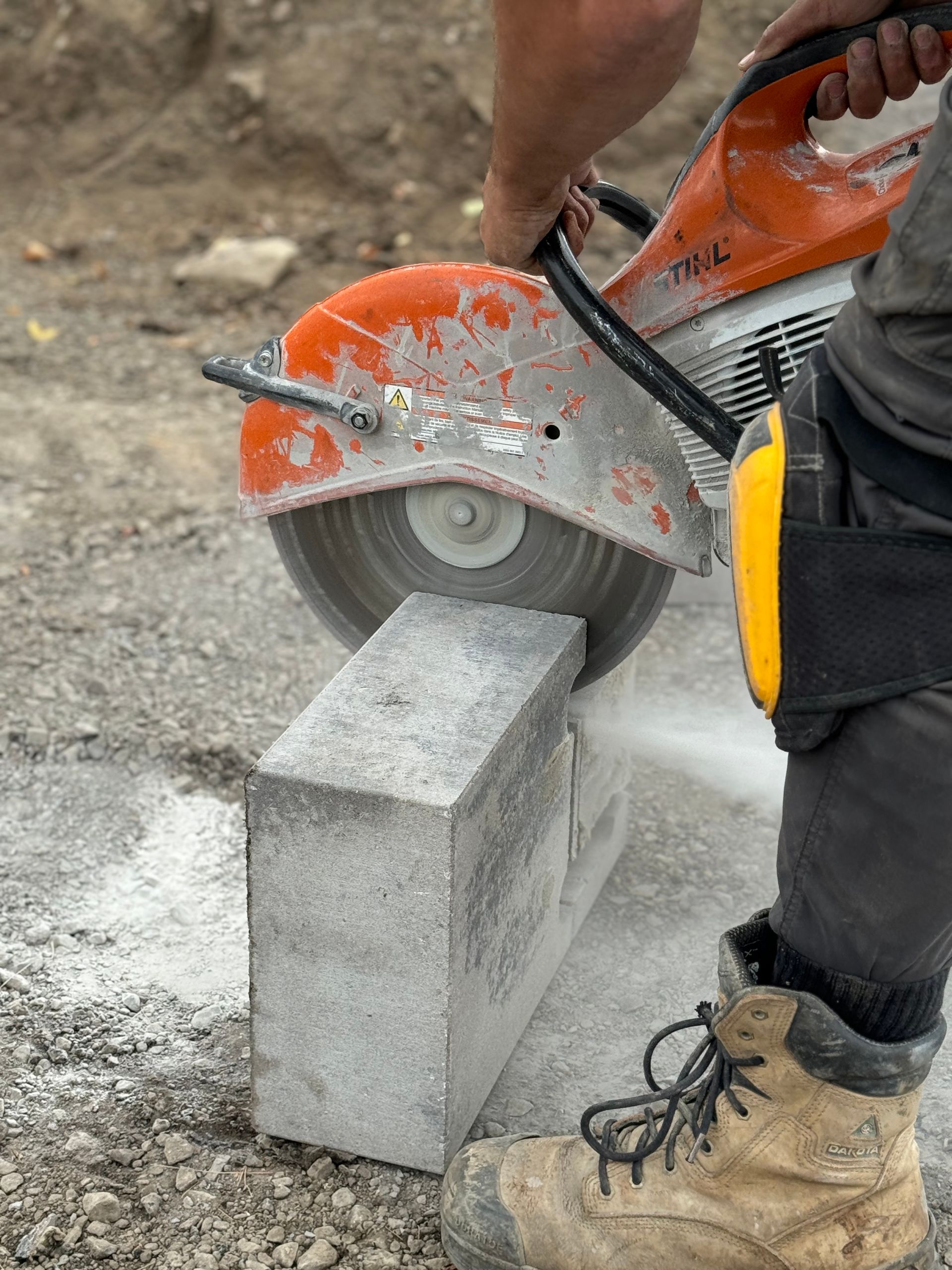 Une personne coupe une brique avec une scie circulaire.