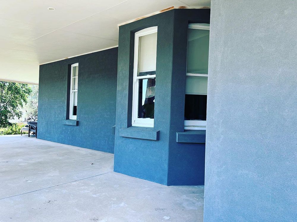A Blue House With White Windows and a Concrete Porch — S & S Tiling and Rendering in Coonamble, NSW