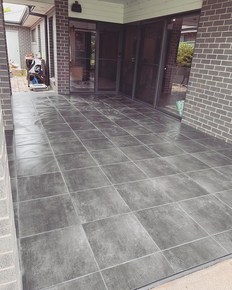 A Tiled Patio With a Brick Wall and Sliding Glass Doors — S & S Tiling and Rendering in Walgett, NSW