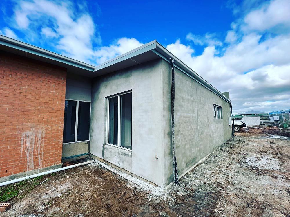 A House is Being Built in a Dirt Field With a Blue Sky in the Background — S & S Tiling and Rendering in Walgett, NSW