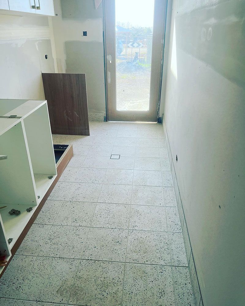 A Kitchen Under Construction With a Tiled Floor and a Door — S & S Tiling and Rendering in Geurie, NSW