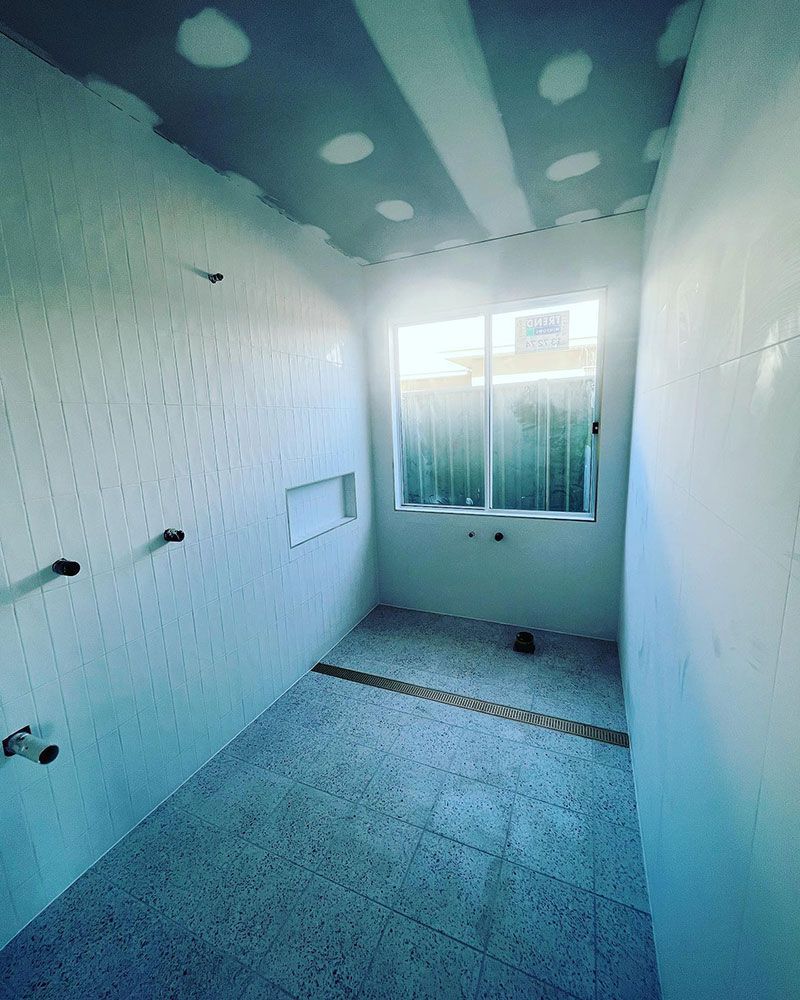 A Bathroom Under Construction With White Tiles and a Window — S & S Tiling and Rendering in Forbes, NSW