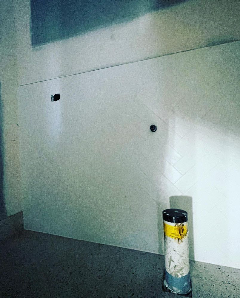 A White Wall With a Black Pipe in the Middle of It — S & S Tiling and Rendering in Geurie, NSW