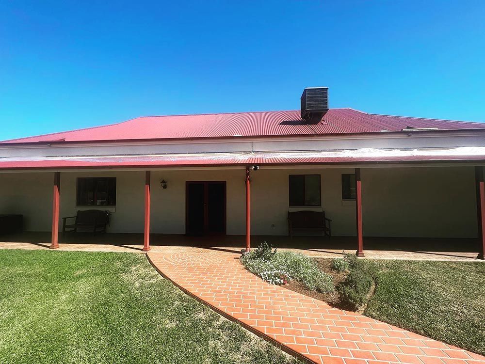 A Large White House With a Red Roof and a Walkway Leading to It — S & S Tiling and Rendering in Coonamble, NSW