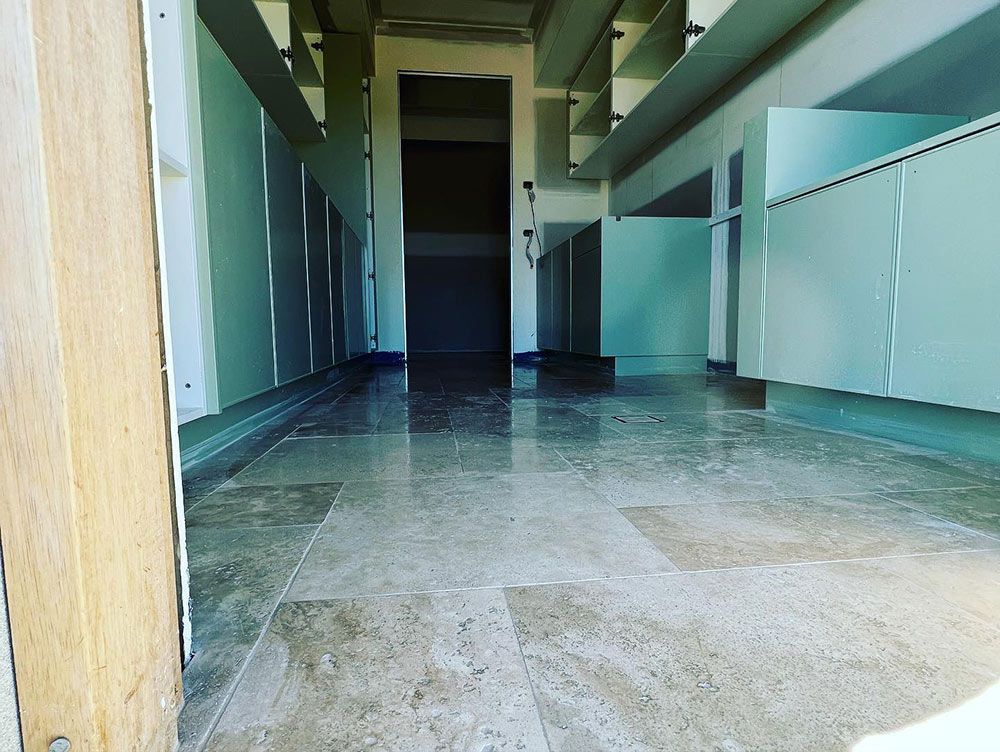 A Hallway With a Marble Floor and White Cabinets — S & S Tiling and Rendering in Orange, NSW