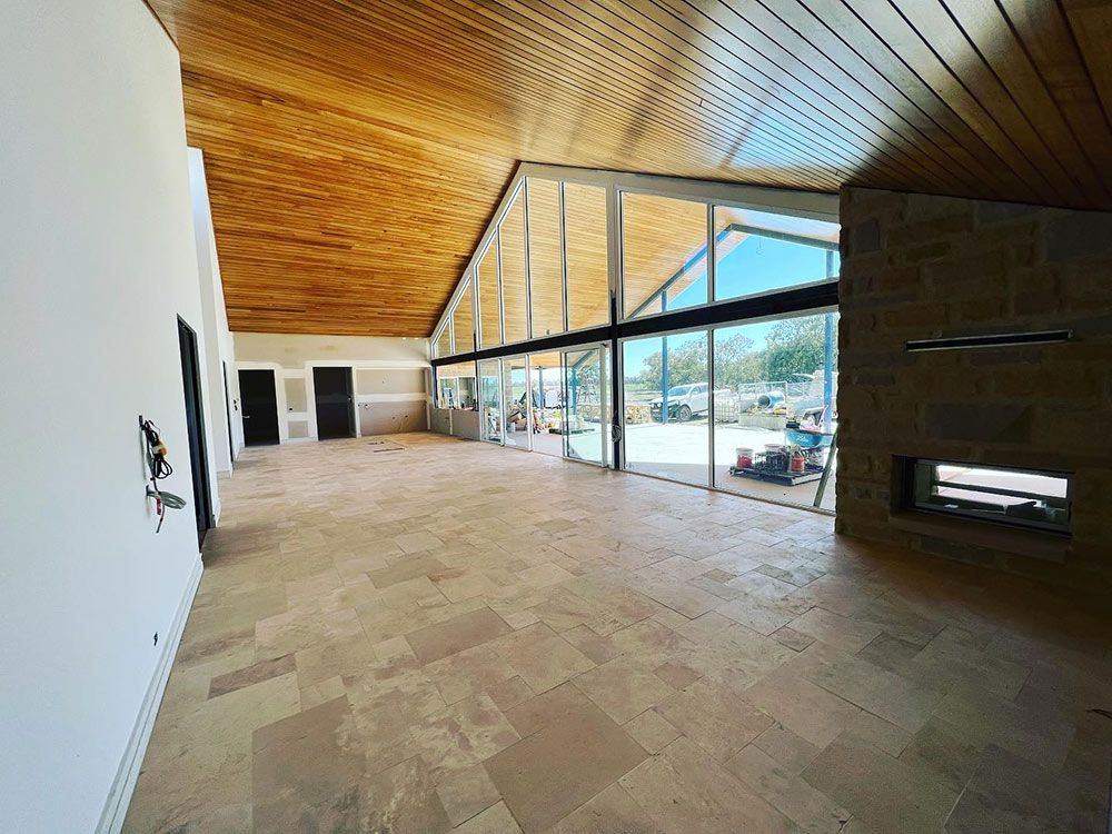 A Large Empty Room With a Wooden Ceiling and a Fireplace — S & S Tiling and Rendering in Walgett, NSW