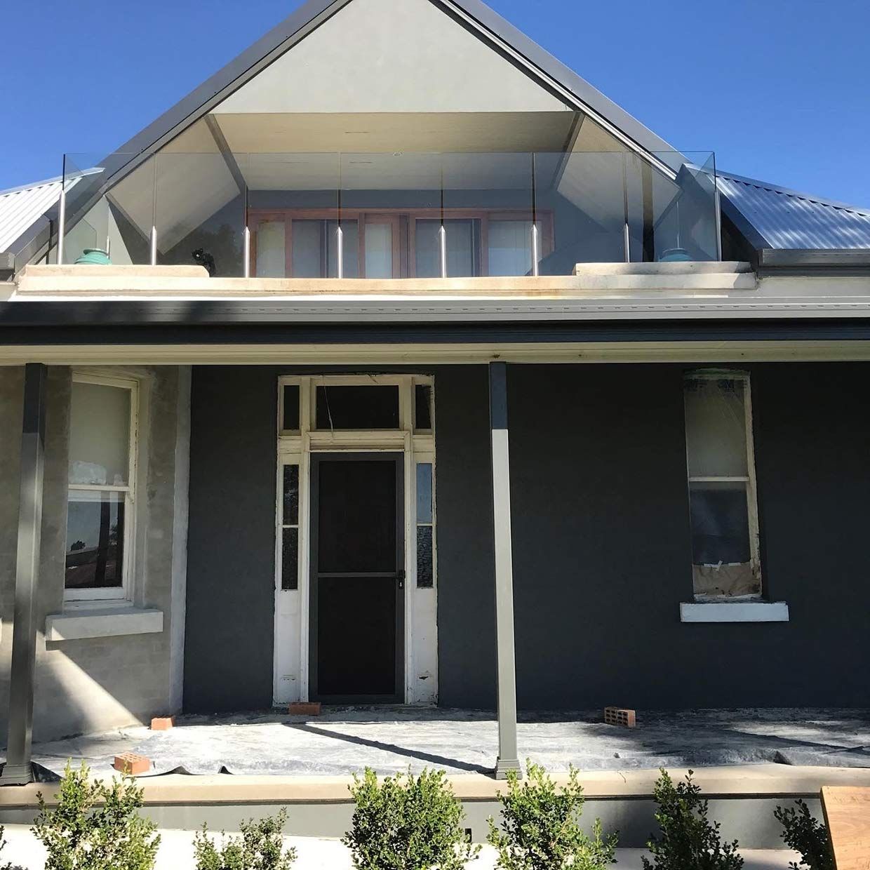 A Gray House With a Balcony on Top of It — S & S Tiling and Rendering in Forbes, NSW