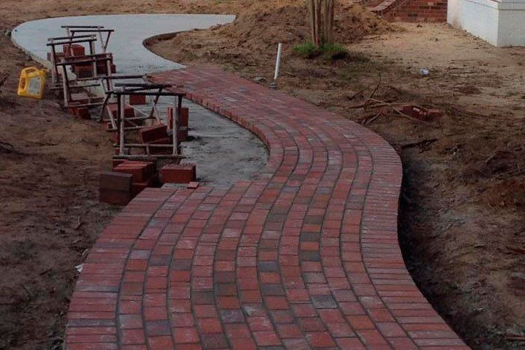 A brick walkway is being built next to a concrete walkway.