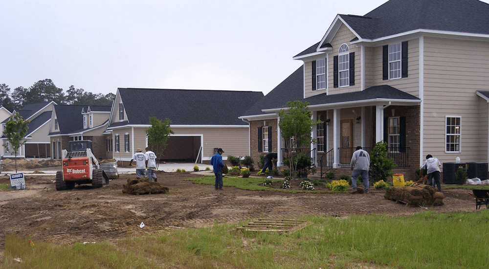 A group of people are working in front of a large house.
