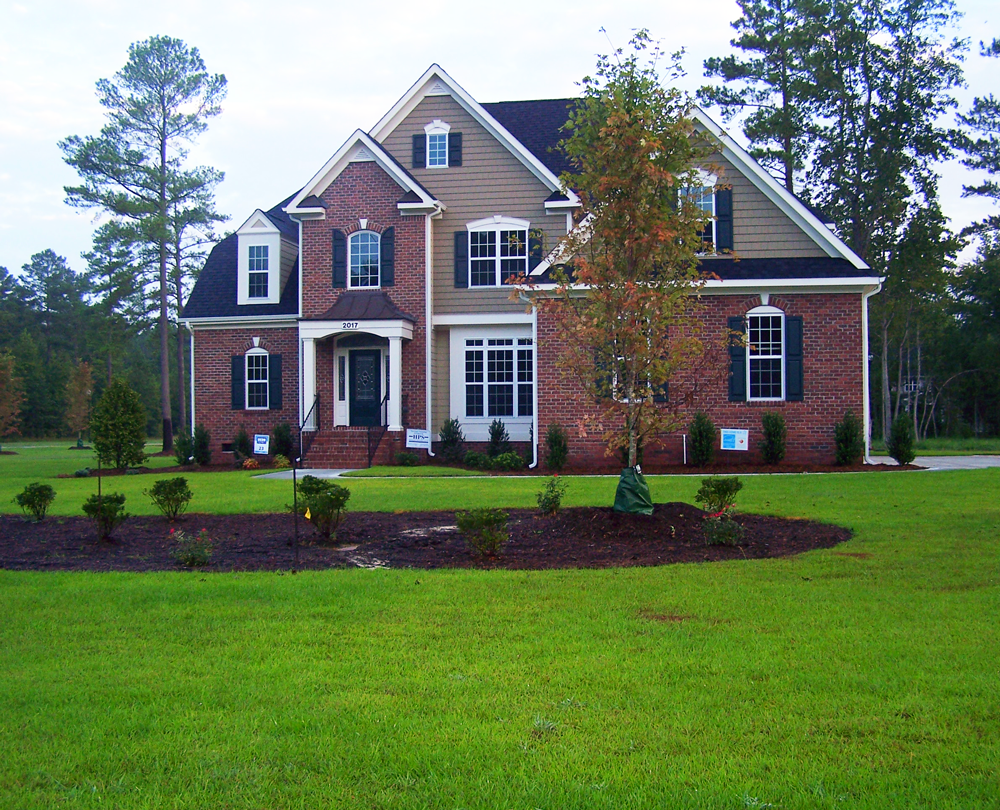 A large brick house with a lush green lawn in front of it