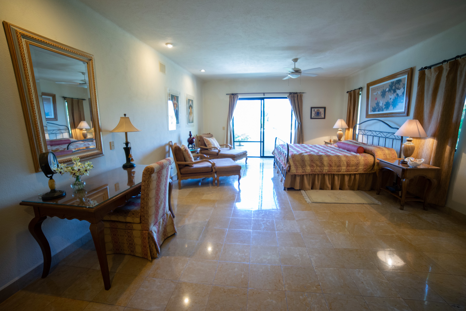 a  room with bed , a desk , chairs , lamps and a large window .