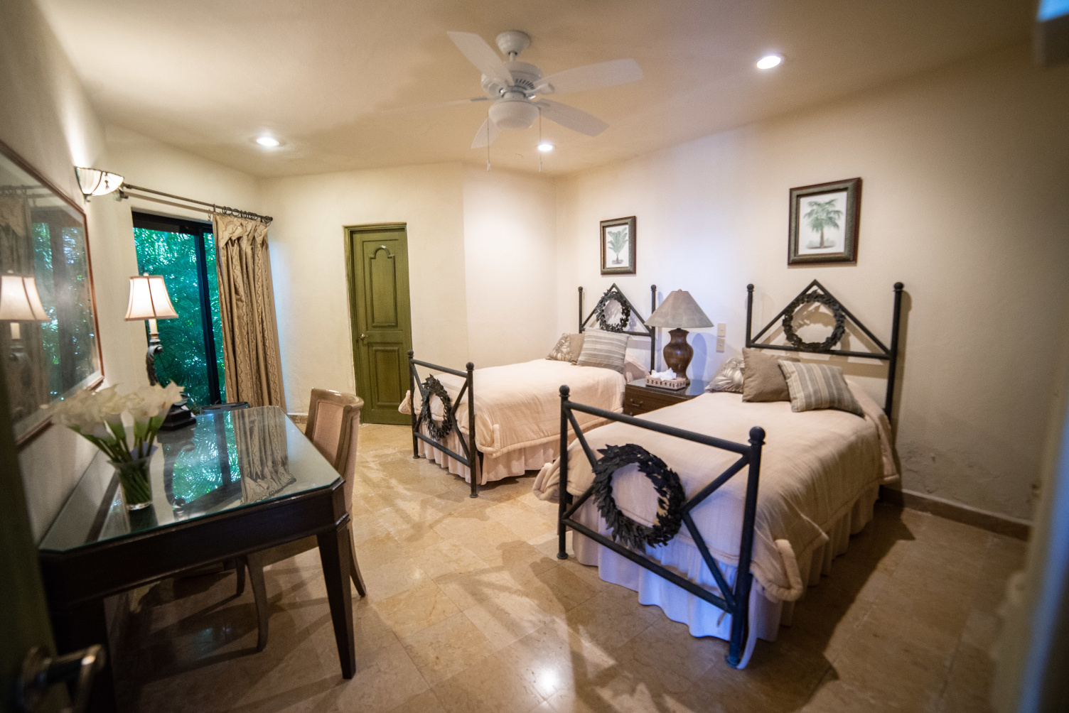 a bedroom with two beds , a desk and a ceiling fan .