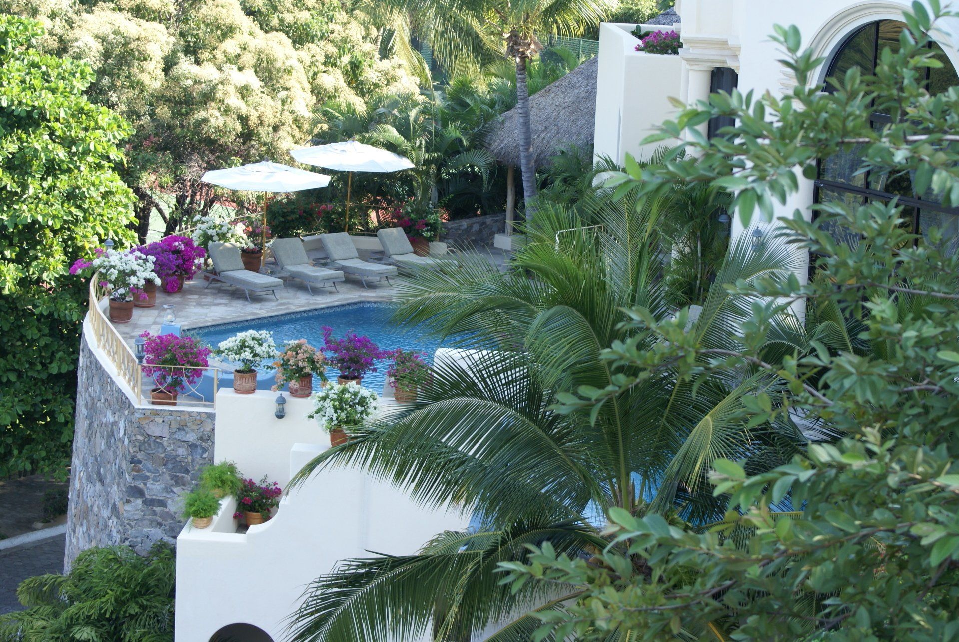 a large white building with a swimming pool surrounded by trees