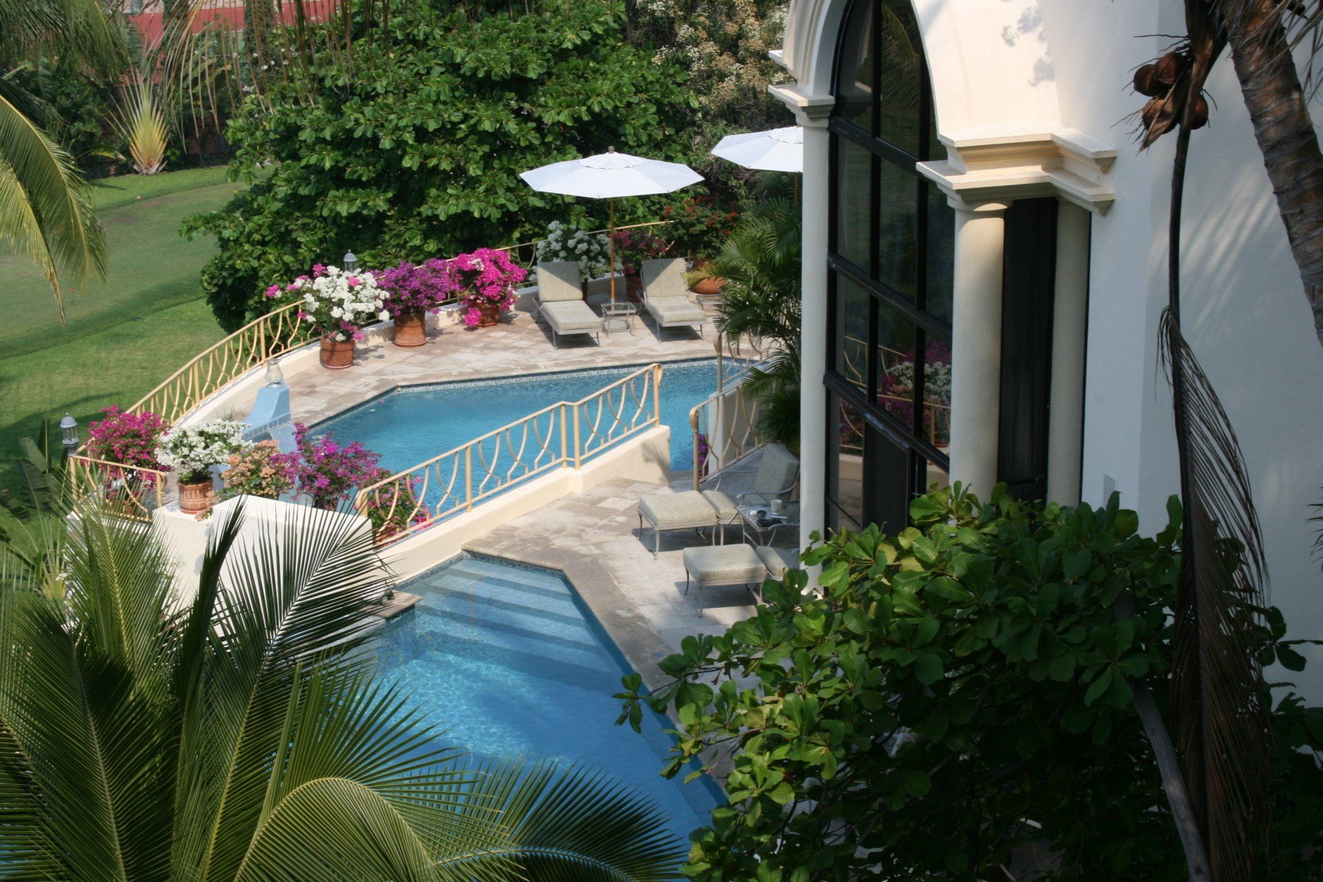 an aerial view of a large swimming pool surrounded by palm trees